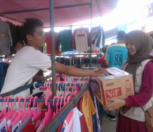 Volunteer STF UIN Jakarta Galang Dana Bantu Korban Selat Sunda Pedagang sedang memberikan donasinya ke dalam kotak donasi melalui volunteer yang sedang menggalang dana untuk korban bencana Tsunami Selat Sunda. Kegiatan Berlangsung di Pasar Pagi kampus II UIN Jakarta pada 30 Desember 2018.